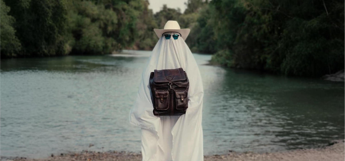 a person in a white sheet with a bag and sunglasses